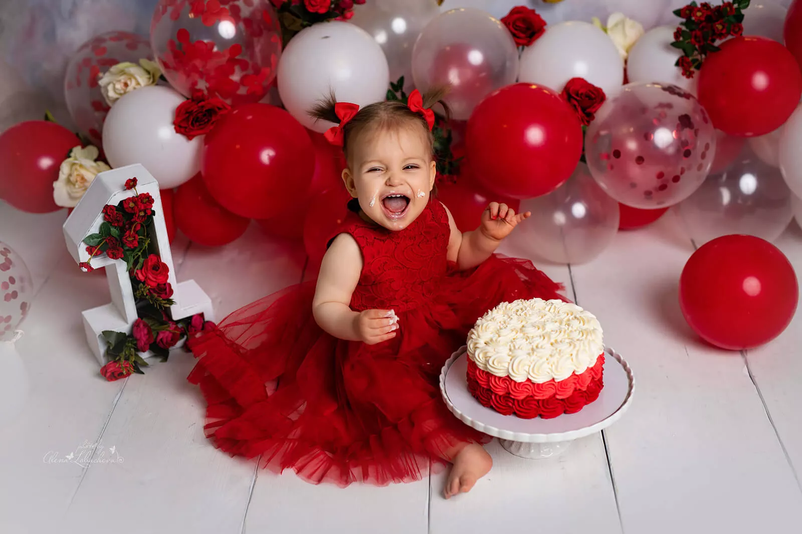 Baby girl celebrating her first birthday with strawberries and balloons