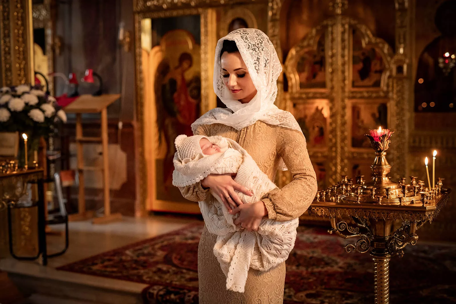 Mother holding her christened baby inside an ornate Orthodox church