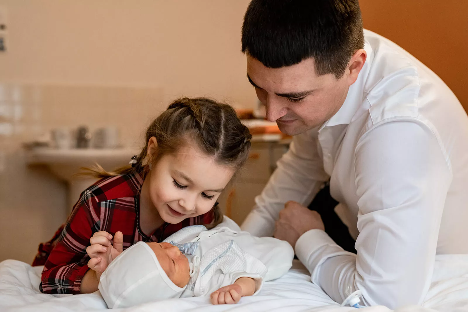 Father and older sister looking at the newborn baby together