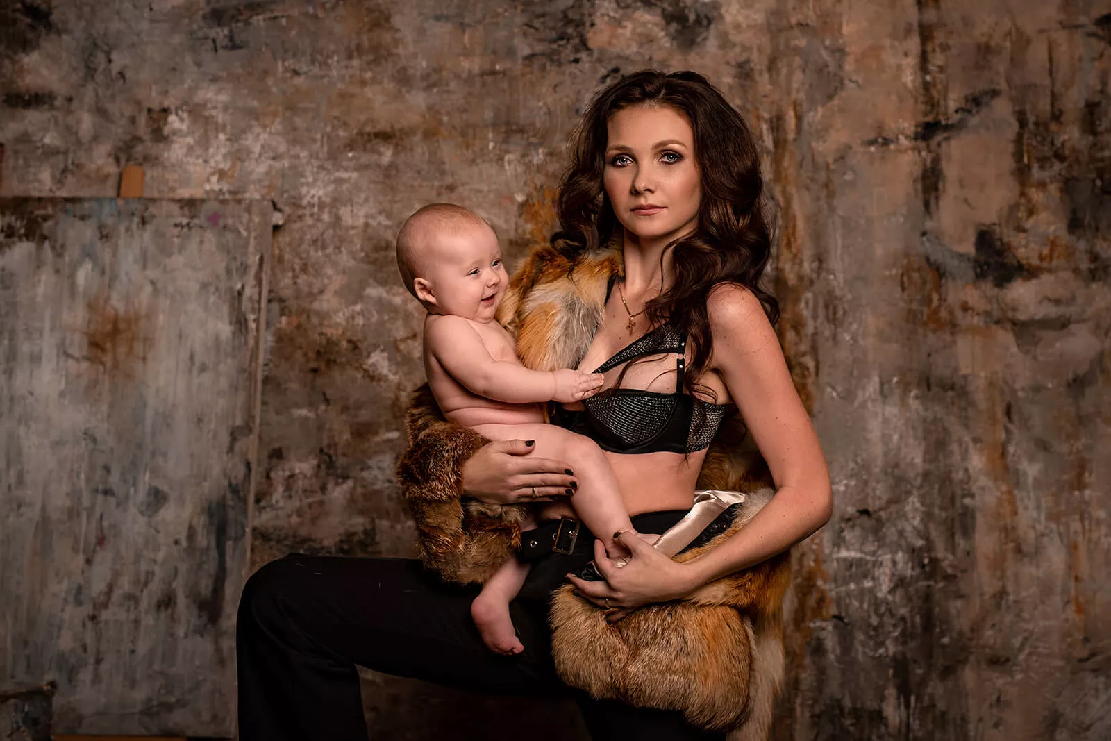 Mother holding her baby against a textured studio wall
