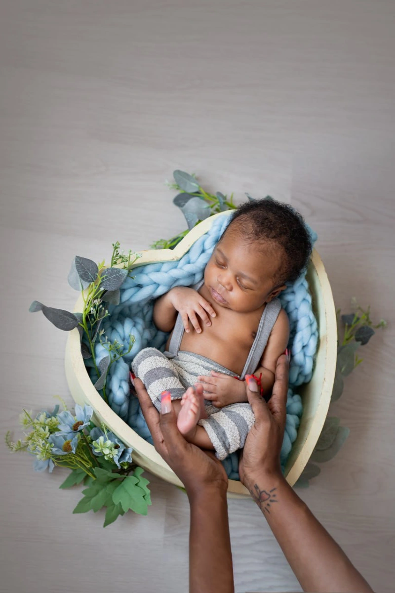 Newborn baby posed with wraps and props during a styled session